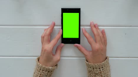 Woman-looking-at-smartphone-with-green-screen