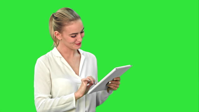 Schöne-junge-Frau-lachend-beim-betrachten-digital-Tablette-auf-einem-Green-Screen,-Chroma-Key