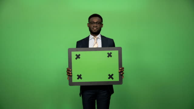 Smiling-african-businessman-holding-chromakey-board