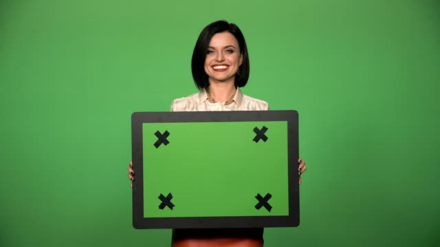Smiling-confident-businesswoman-holding-chromakey-board