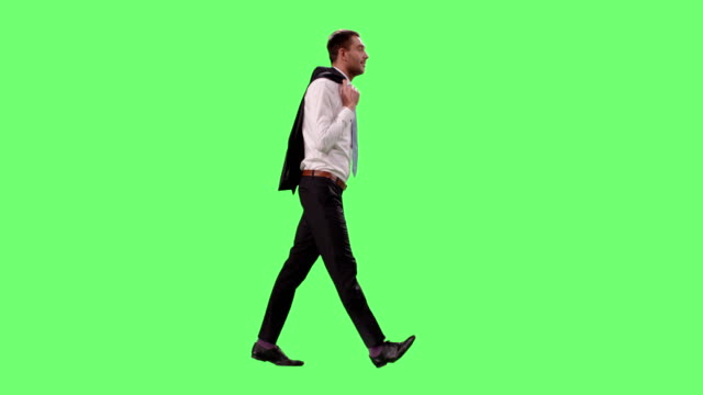Young-Successful-Businessman-in-a-Suit-Enjoys-Good-Weather-Throws-Jacket-over-the-Shoulder-While-Walking.-Shot-on-Mock-up-Green-Screen.
