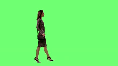 Mujer-morena-glamorosa-en-un-Vestido-ajustado-con-un-monedero-pequeño-caminar-elegantemente-sobre-una-maqueta-verde-pantalla-de-fondo.