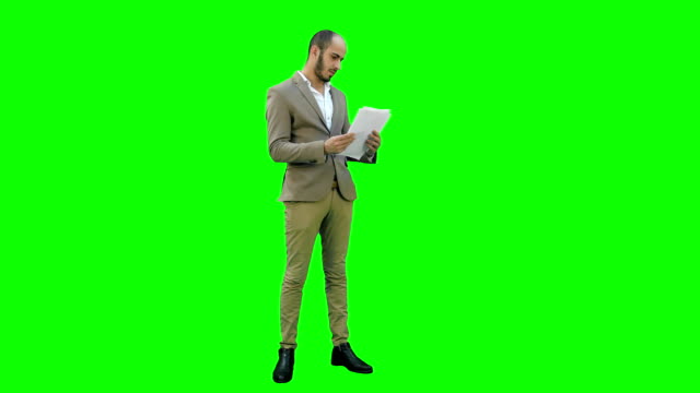 Young-businessman-attentively-studying-documents-on-a-Green-Screen,-Chroma-Key