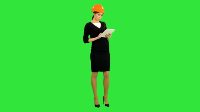 Female-architect-in-hardhat-holding-tablet-and-making-inspection-on-a-Green-Screen,-Chroma-Key