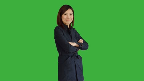 Junge-asiatische-Frau-trägt-einen-blauen-Mantel.-Verwendung-von-Smartphone,-Digital-Tablette-und-Blick-in-die-Kamera.-Frau-stand-vor-einem-Greenscreen-für-Chroma-Key.