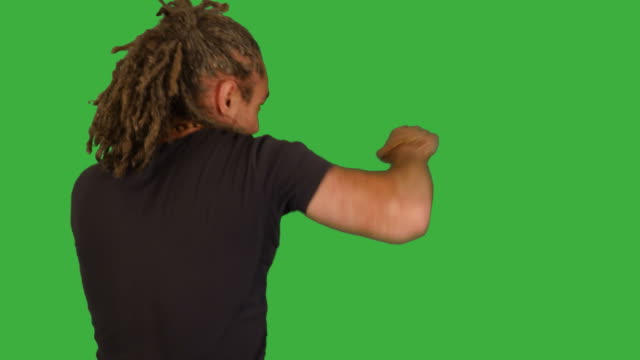Mid-Aged-Man-Fighting-in-Front-of-a-Green-Screen.-Preparing-for-Combat-and-Beating-towards-Camera.-Dreadlocks-and-Black-T-Shirt.