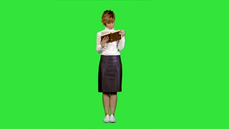 Woman-standing-and-reading-book-on-a-Green-Screen,-Chroma-Key