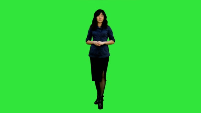 Mujer-asiática-atractiva-joven-habla-a-cámara,-que-presenta-algo-en-una-pantalla-verde-Chroma-Key