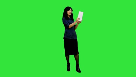Asian-lady-having-video-chat-using-a-tablet-on-a-Green-Screen,-Chroma-Key