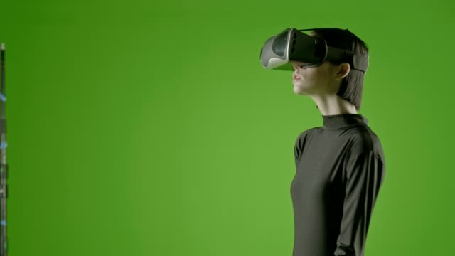 Attraktives-Mädchen-junge-Mode-Modell-tragen-eine-VR-Kopfhörer-in-green-Screen-gedreht