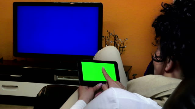 Rückansicht-der-Frau-verwenden-zu-Hause-elektronische-Tablet-und-smart-tv.-UHD-Lager-video,-alpha-Matte-inklusive