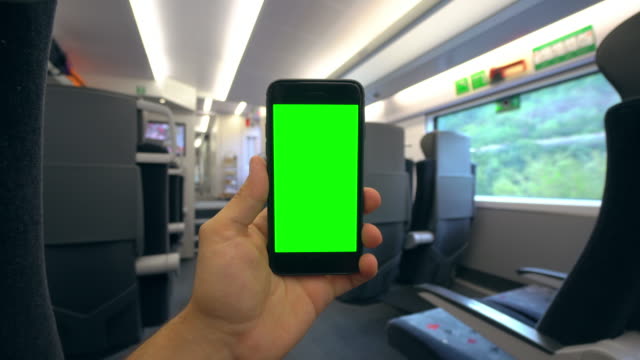 Hand-Holding-a-Phone-with-a-Green-Screen-on-the-Train