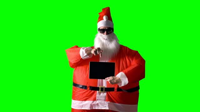 Santa-Claus-on-a-green-background-holds-a-tablet-PC.
