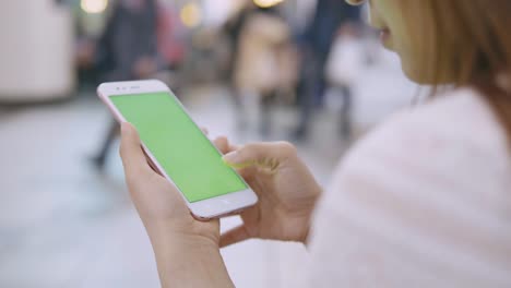 Woman-using-smartphone-with-green-screen-on-the-street.