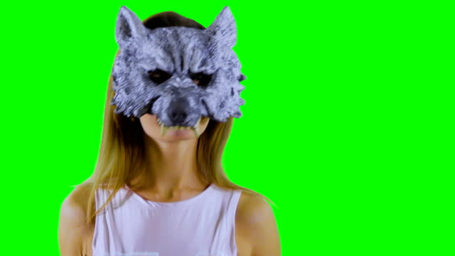 Glückliche-Mädchen-trägt-wolf-Maskentänze-auf-grünem-Hintergrund-und-Daumen-nach-oben-zeigt