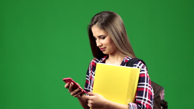 Attraktive-junge-Studentin,-die-mit-ihrem-Smartphone-in-die-Kamera-Lächeln