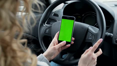 Woman-sits-in-the-modern-car-and-works-on-smartphone---closeup-hands.-Green-screen.Chroma-key