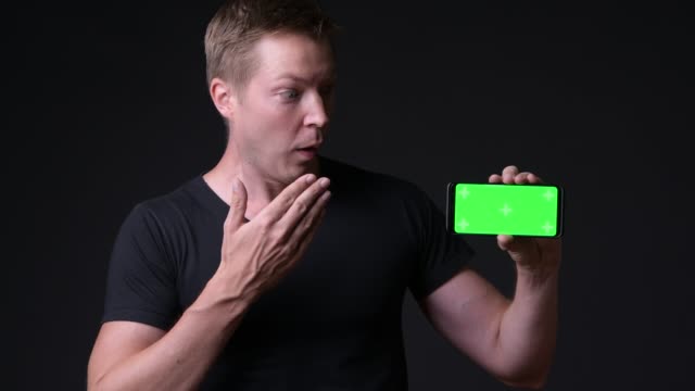 Surprised-Man-Holding-Mobile-Phone-With-Chroma-Key-Green-Screen