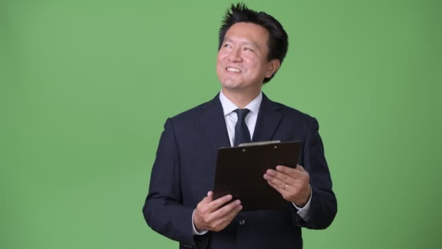 Reife-japanischer-Geschäftsmann-vor-grünem-Hintergrund