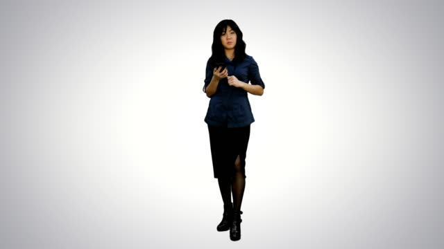 Jóvenes-mujeres-asiáticas-con-smartphone-de-pie-y-hablando-con-una-cámara-sobre-fondo-blanco