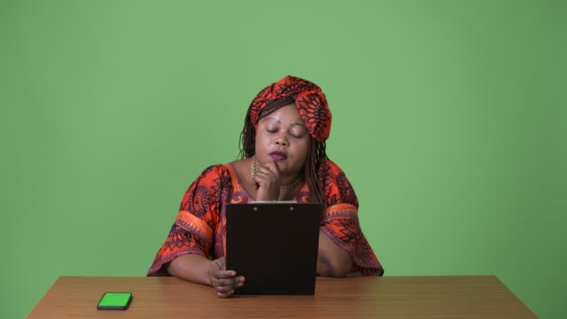 Overweight-beautiful-African-woman-wearing-traditional-clothing-against-green-background