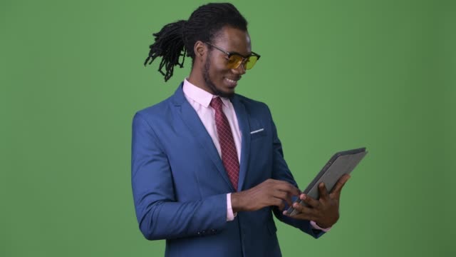 Young-handsome-African-businessman-with-dreadlocks-against-green-background