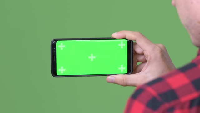 Young-Scandinavian-businessman-using-mobile-phone-against-green-background