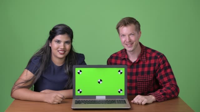 Young-multi-ethnic-business-couple-together-against-green-background