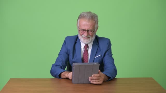 Gut-aussehend-senior-bärtigen-Geschäftsmann-vor-grünem-Hintergrund