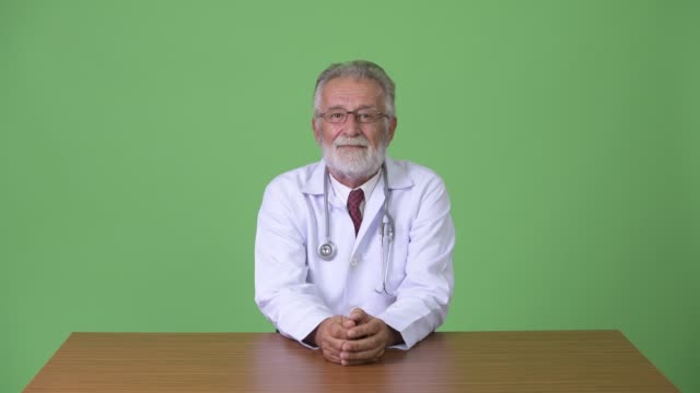 Médico-guapo-barba-senior-sobre-fondo-verde