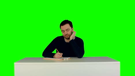 Pensive-student-listening-to-lecture-in-university-and-taking-notes-on-a-Green-Screen