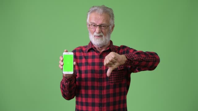 Gut-aussehend-Senior-bärtiger-Mann-vor-grünem-Hintergrund