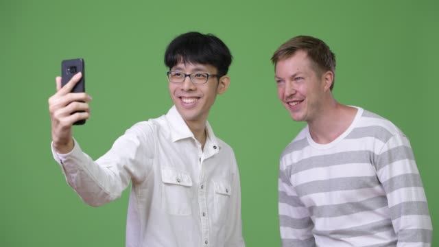 Zwei-glückliche-multiethnischen-Jungunternehmer-Lächeln-während-der-Einnahme-von-Selfie-zusammen