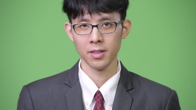 Junge-asiatische-Geschäftsmann-vor-grünem-Hintergrund