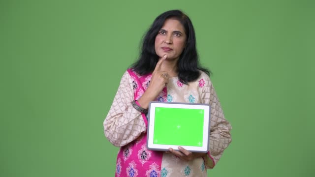 Reife-schöne-indische-Frau-denken-und-zeigt-digital-Tablette