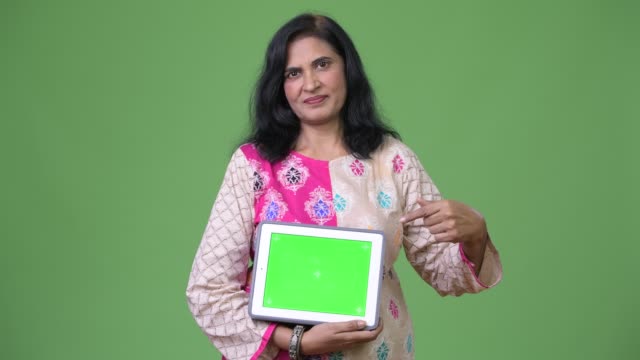 Reife-schöne-Inderin-zeigt-digital-Tablette-und-Zeigefinger