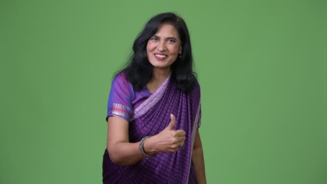 Madura-feliz-hermosa-mujer-India-dando-pulgares-usando-la-vestimenta-tradicional-de-Sari