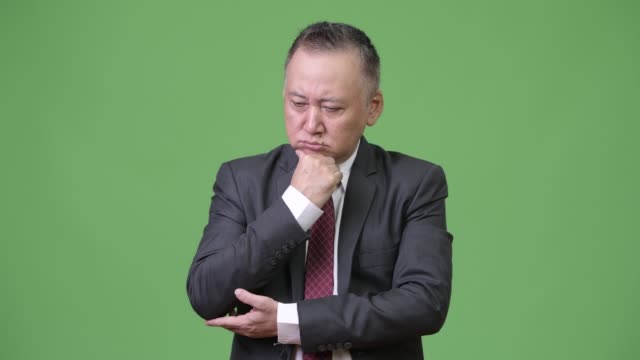 Mature-stressed-Japanese-businessman-looking-down-while-thinking