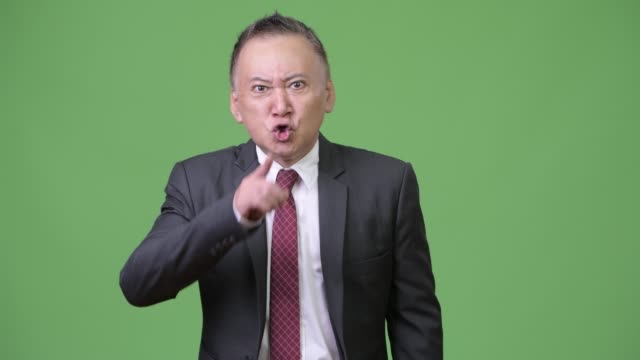 Reife-wütend-japanischer-Geschäftsmann-mit-Finger-auf-die-Lippen