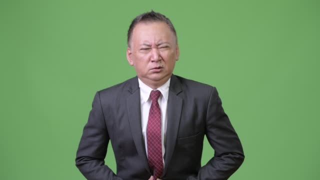 Reife-japanischer-Geschäftsmann-mit-Magenschmerzen