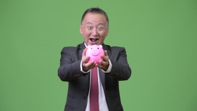 Reife-japanischer-Geschäftsmann-hält-Sparschwein