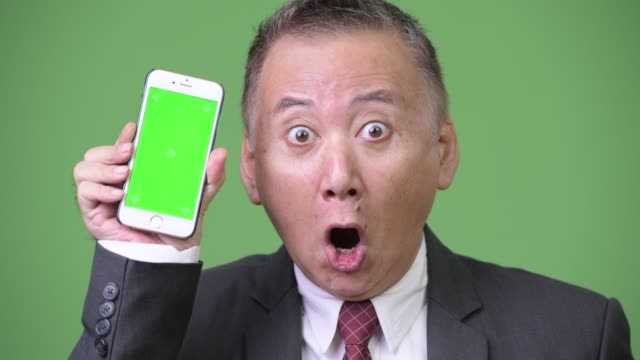 Reife-japanischer-Geschäftsmann-zeigen-Telefon-mit-Kamera