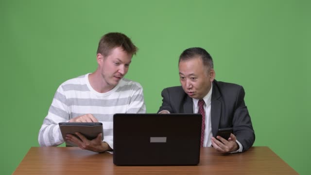 Mature-Japanese-businessman-and-young-Scandinavian-businessman-working-together