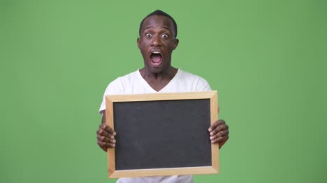 Young-African-man-showing-blackboard-and-looking-shocked