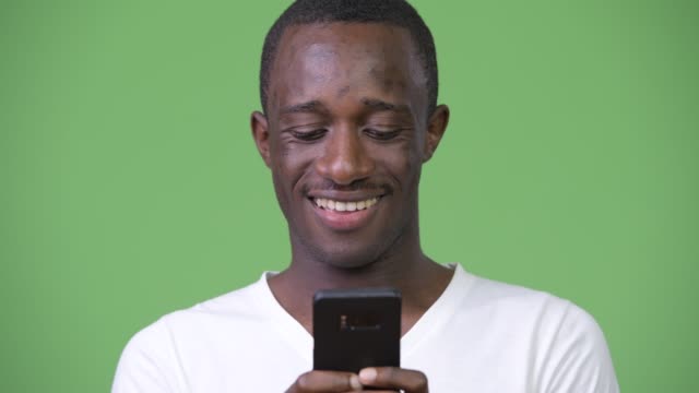 Young-African-man-using-phone-against-green-background