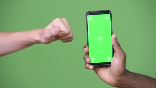 Two-multi-ethnic-hands-showing-phone-while-giving-thumbs-down