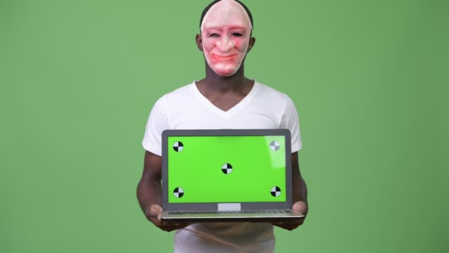 Junge-afrikanische-Mann-tragen-Maske-beim-Laptop-zeigen