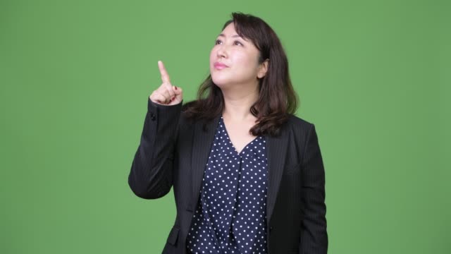Mature-beautiful-Asian-businesswoman-thinking-while-pointing-finger-up