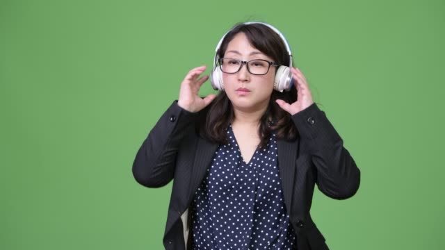 Mature-beautiful-Asian-businesswoman-listening-to-music