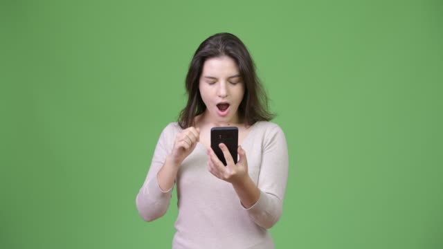 Young-beautiful-woman-looking-shocked-while-using-phone